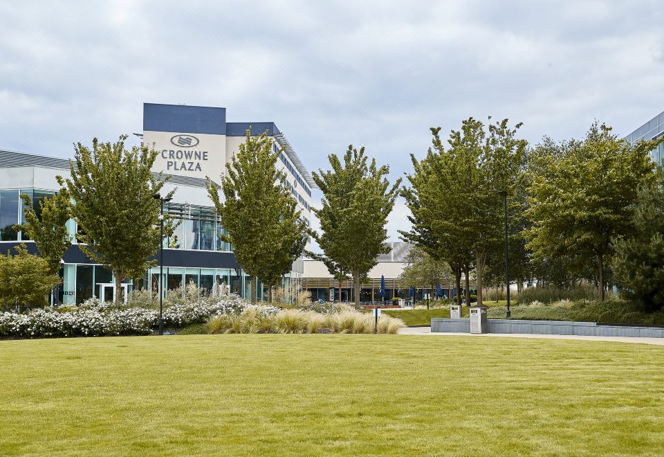"a large building with a sign that reads "" crowne plaza "" is surrounded by trees and grass" at Crowne Plaza Reading East