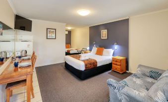 a hotel room with a bed , nightstands , and lamps , as well as a couch and other furniture at Best Western Caboolture Gateway Motel