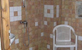 a white chair is placed in a bathroom with orange and white tiles , next to a shower head at La Bergerie