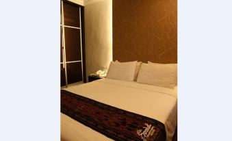 a bed with white sheets and a brown blanket is in a room with brown walls at Royal Hotel