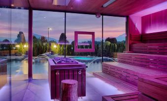 a modern spa with purple lights , wooden benches , and a large window overlooking a pool at Majestic Hotel & Spa Resort