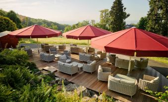 a group of lounge chairs and umbrellas are set up on a wooden deck with a view of the mountains at Falkenstein Grand, Autograph Collection