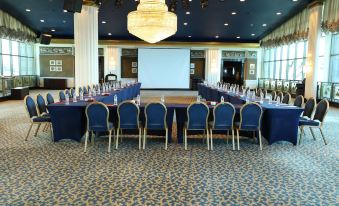 a conference room set up for a meeting , with rows of chairs arranged in a semicircle and a projection screen on the wall at Le Royal Hotel - Beirut