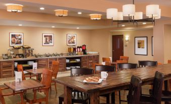 a dining area with wooden tables and chairs , as well as a buffet table with food at DoubleTree by Hilton Portland - Tigard