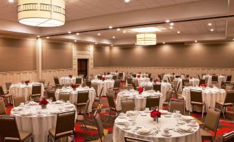 a large banquet hall filled with round tables and chairs , ready for a formal event at Four Points by Sheraton Saginaw