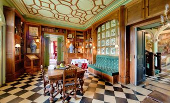 a dining room with a checkered floor , wooden table , and chairs , as well as a green couch at Chateau de la Bourdaisiere