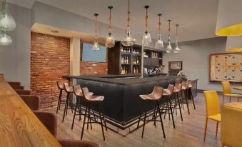 a modern bar with black countertops and chairs , surrounded by hanging lights and a brick wall at Scholar Morgantown, Tapestry Collection by Hilton