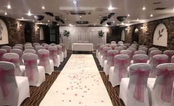 a wedding ceremony is taking place in a spacious room with rows of chairs and pink flowers on the aisle at Best Western Bradford Guide Post Hotel