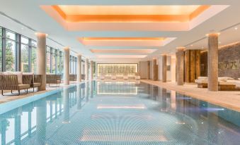 a large indoor swimming pool surrounded by lounge chairs and a staircase leading up to the second floor at Galgorm
