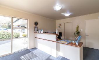 a clean and well - organized office space with a reception desk , several chairs , and a couch at Admirals Motor Inn