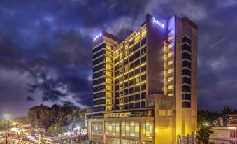 a large hotel building lit up at night , surrounded by a parking lot and people at Radisson Blu Gorakhpur