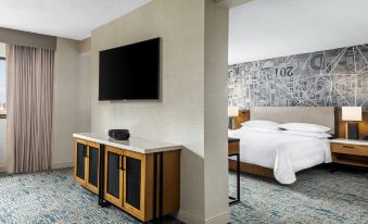 a hotel room with a bed , a tv , and a large flat - screen tv mounted on the wall at Sheraton Philadelphia Downtown