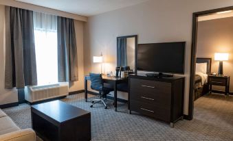 a hotel room with a large flat - screen tv mounted on the wall , a desk , and a chair at Wingate by Wyndham Angola