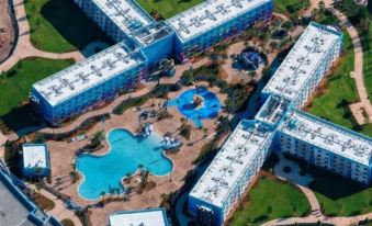 a bird 's eye view of a large , blue - roofed resort with multiple buildings and a swimming pool at Disney's Art of Animation Resort