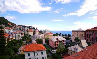a picturesque view of a town with houses and the ocean in the background , under a blue sky dotted with clouds at Hotel Le Palme