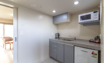 a small , white - walled kitchen with stainless steel appliances and a microwave oven on the wall at Admirals Motor Inn