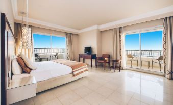 a luxurious bedroom with a large bed , white walls , and a balcony offering a view of the ocean at Iberostar Selection Royal El Mansour