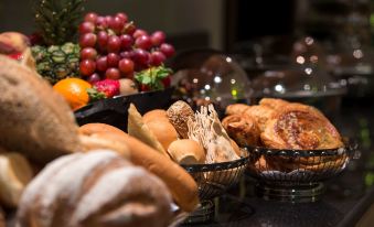 a variety of baked goods , including bread and pastries , are displayed in black baskets on a table at Park Inn by Radisson Dammam