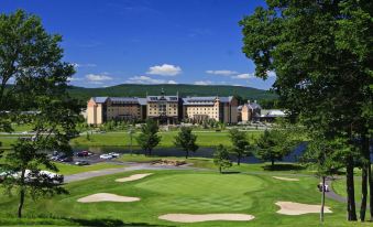 a golf course with a large building in the background , surrounded by trees and grass at Mount Airy Casino Resort - Adults Only