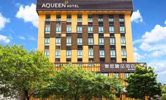 "a tall , yellow hotel building with a black sign that says "" aqueen hotel "" in front of trees and under a clear blue sky" at AQUEEN HOTEL