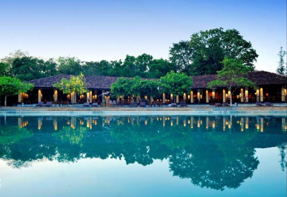 a resort with a large pool surrounded by trees and a gazebo , providing a serene atmosphere for guests at Habarana Village by Cinnamon