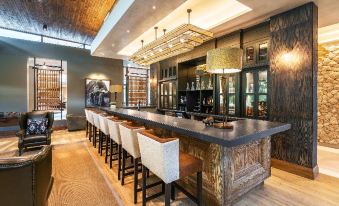 a modern bar with a long wooden counter and several stools , creating an inviting atmosphere at Mokuti Etosha