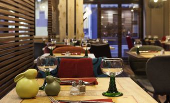 a table is set with wine glasses , forks , knives , and a vase of green flowers at Ibis Styles Chaumont Centre Gare