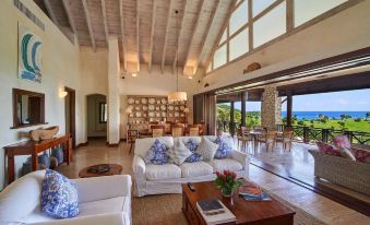 a spacious living room with a couch , chairs , and a dining table in the background at Mandarin Oriental, Canouan