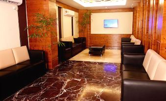a large room with wooden walls and a marble floor has black leather couches and a television at Imperial Heights