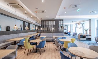 a modern restaurant with multiple dining tables and chairs arranged in an open space , creating an inviting atmosphere at Hampton by Hilton Oswiecim