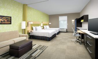 a modern hotel room with two beds , a couch , and various office equipment , all arranged in a comfortable layout at Home2 Suites by Hilton Lake City