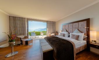 a spacious bedroom with a large bed , wooden floors , and a balcony overlooking a beautiful mountain view at Le Mirador Resort and Spa