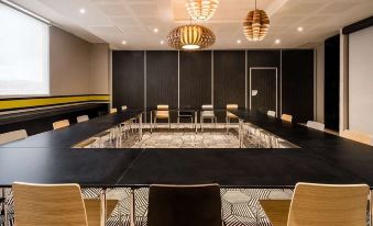 a large conference room with a black table and chairs , surrounded by black walls and hanging lights at Simon Hotel