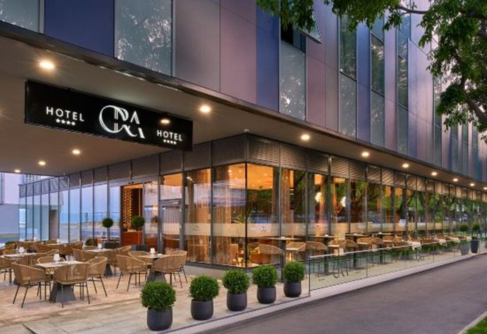 a modern hotel building with a restaurant and outdoor seating area , set against the backdrop of a city skyline at Sia Split Hotel
