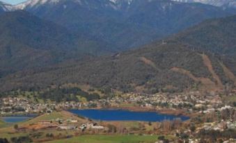 a scenic view of a mountainous landscape with a small town nestled in the valley , surrounded by snow - capped mountains at Mount Beauty Motor Inn