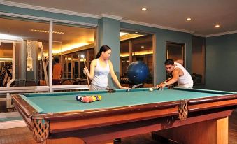 a man and a woman are playing pool in a room with a blue ball on the table at MetroCentre Hotel