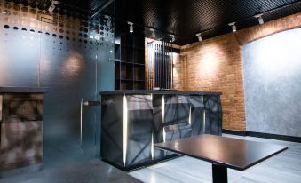 a modern , industrial - style room with exposed brick walls and black walls , featuring a dining table and a bar at Fabrika