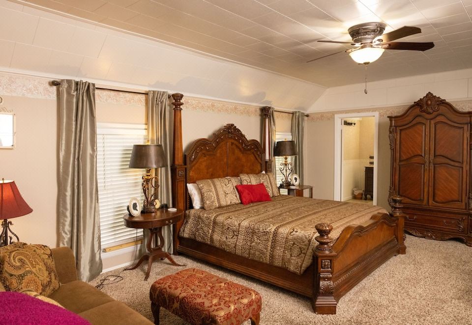a large bed with a wooden headboard and footboard is in the middle of a room with multiple lamps and a chandelier at Sassafras Inn