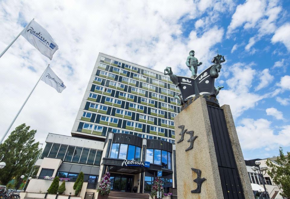 a large building with a statue of a woman in front of it , possibly a hotel at Radisson Blu Caledonien Hotel, Kristiansand