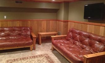 a cozy living room with wooden walls , red leather couches , and a rug on the floor at Cranberry Inn