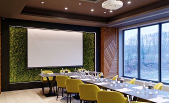 a modern conference room with yellow chairs , white tables , and a large screen on the wall at Hotel Victory