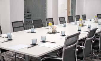 a conference room with a long white table surrounded by black chairs and various items on it at Mercure Newport