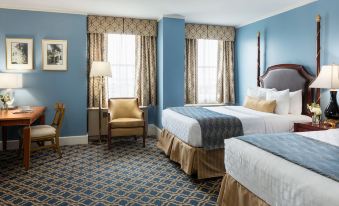 a hotel room with two beds , a chair , and windows covered in blue curtains , all decorated in a modern style at Francis Marion Hotel