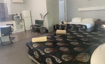 a bedroom with two beds , one of which has a floral bedspread , and a fridge in the background at Hillview Motel