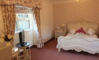 a bedroom with a white bed , pink carpet , and a chandelier hanging from the ceiling at Glenspean Lodge Hotel