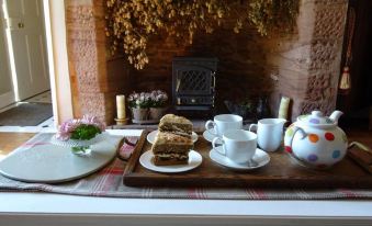 a wooden dining table with a tray of food and a tea kettle on it at Moor Court Farm