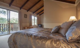 a large bed with a gold - colored blanket is situated in a room with wooden beams and a window at William Bay Cottages