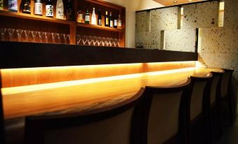 a wooden bar with a curved top , surrounded by shelves filled with bottles and glasses at Hotel Resol Machida
