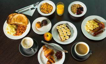 a dining table with a variety of food items , including plates of pancakes , croissants , fruit , and other dishes at Holiday Inn Express Stafford