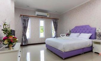 a large , white bedroom with a purple bed and a heart - shaped stuffed animal on the bed at Belleville Hotel